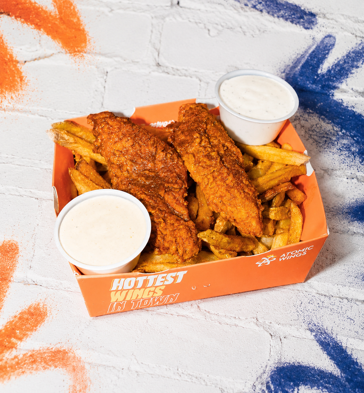 Atomic Wings tenders and fries on a white graffiti brick background